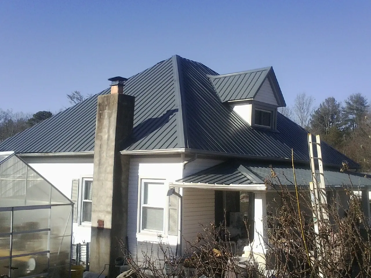 Dark blue standing seam metal roof on a white farmhouse with dormer — Slate & Tile Roof Repair by Roofing Brothers in Ponsford