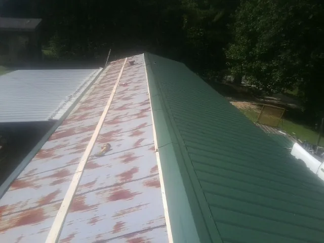 Old rusted panels beside newly installed green metal roofing — Wind Damage Roof Repair by Roofing Brothers in Ponsford
