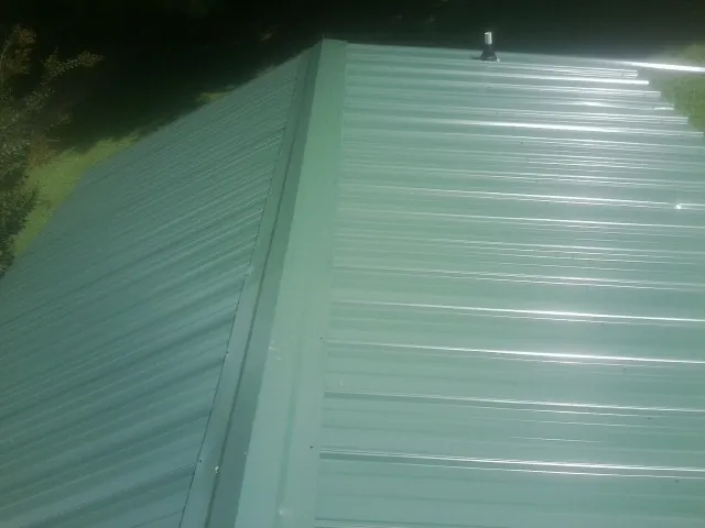 New green metal panels meeting at the ridge of a roof — Flat Roof Repair work by our crew in Ponsford