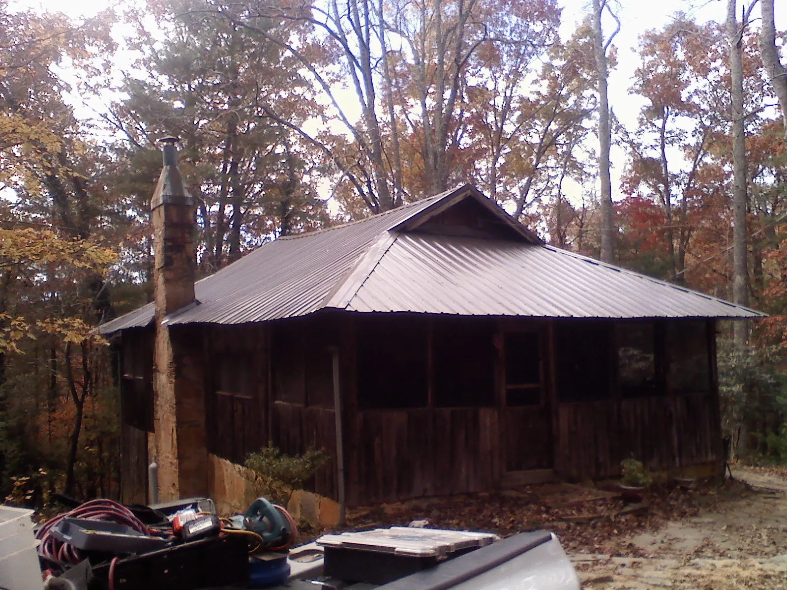 Brown metal hip roof on an old cabin with a stone chimney in Ponsford
