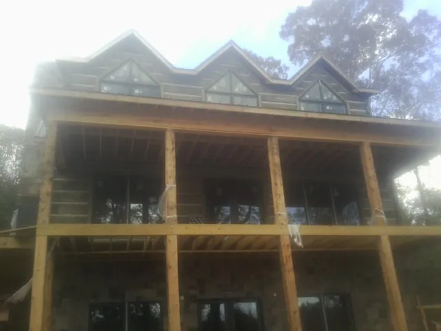 Dormers and porch framing on a large log home under construction — Roof Coating work by our crew in Ponsford