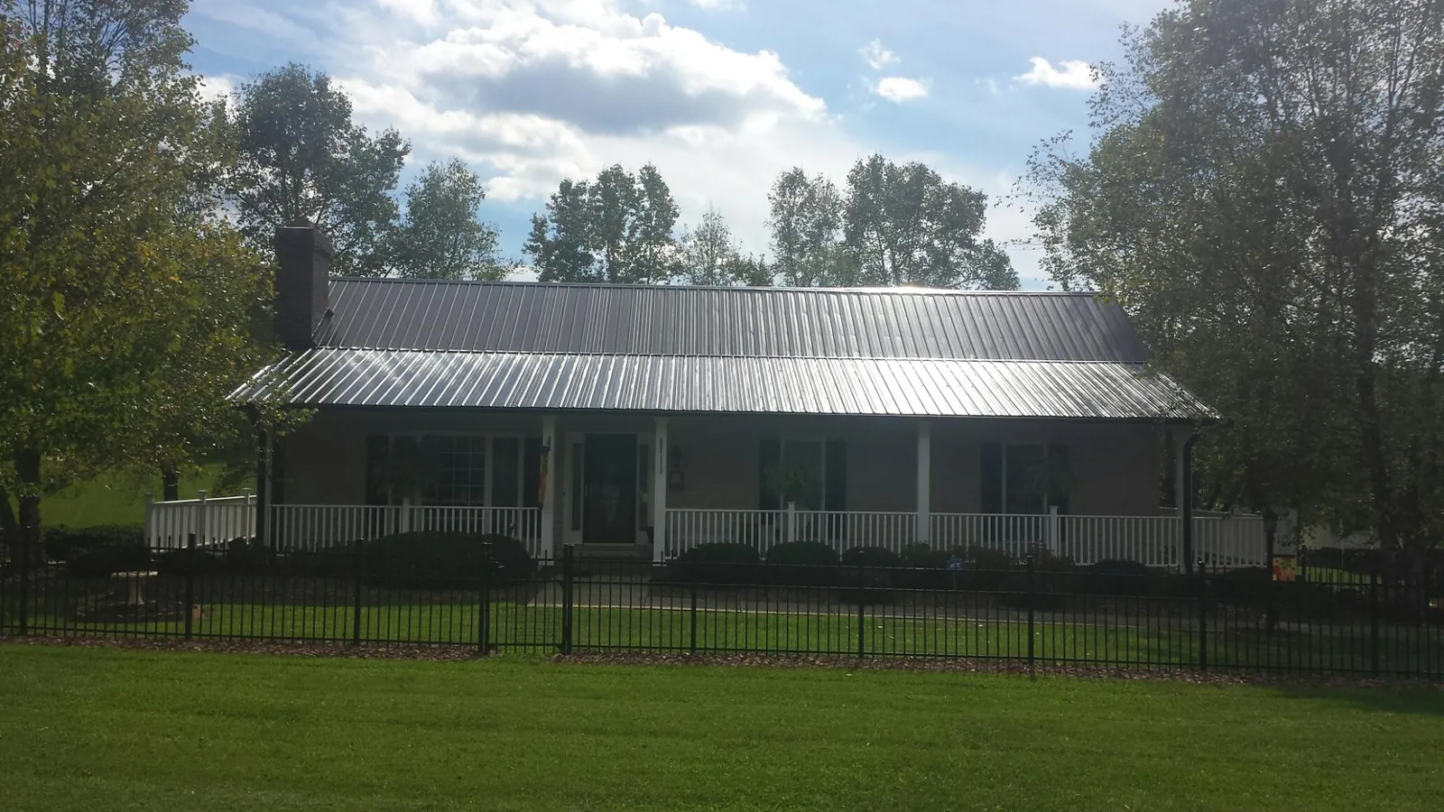 Gray metal roof on a brick ranch with a full width front porch — Gutter Guard Installation work by our crew in Ponsford