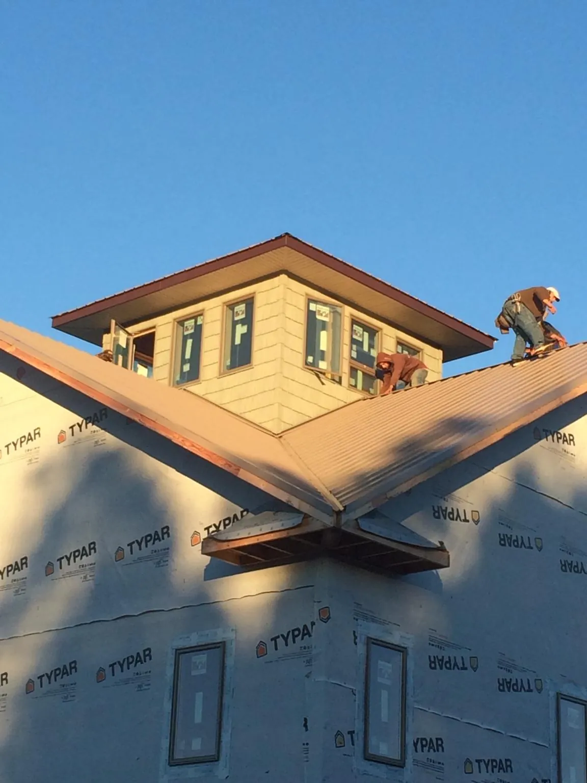 Roofers working around a rooftop cupola on a new metal roof at sunset — Roof Waterproofing in Ponsford by Roofing Brothers